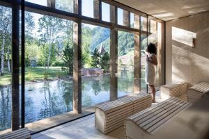 奥蒂塞伊Adler Spa Resort Dolomiti的女人从湖面上大窗户望出去