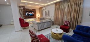 MaiyegunLuxury 3-Bed house in gated estate with pool Lekki的客厅配有沙发、椅子和电视