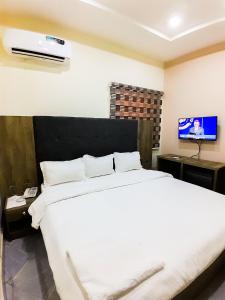 RubuchiCome Inn Hotel的卧室配有白色的床和平面电视。