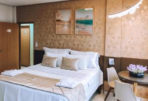 Barra do CordaHOTEL VIANA的卧室配有一张白色的床和桌椅