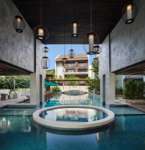 清迈Maladee Rendezvous Hotel Chiang Mai的大楼内的一个蓝色海水游泳池