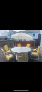 香农河畔卡里克Dublin Road Townhouse的一张带黄色椅子的白色桌子和一把雨伞