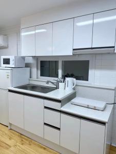 首尔Han Stay的白色的厨房配有白色橱柜和水槽
