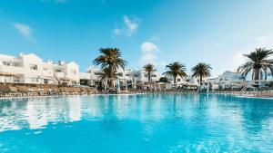 科拉雷侯拉布兰达科拉莱霍村酒店的一座棕榈树和白色建筑的大型游泳池