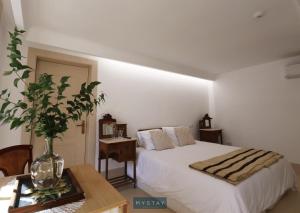 佩纳菲耶尔MyStay - Casa Matriz Séc XVI的一间卧室,配有一张床和一张桌子上的花瓶