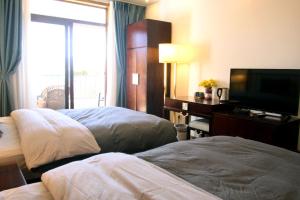 丽江La Maison du Laoshay Lijiang的酒店客房设有两张床和一台平面电视。