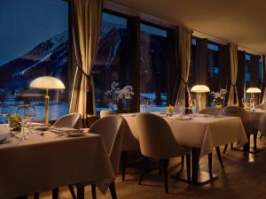 达沃斯Precise Tale Seehof Davos的一间设有白色桌椅和窗户的用餐室