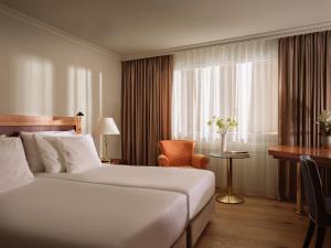 达沃斯Precise Tale Seehof Davos的配有一张床、一张书桌和一扇窗户的酒店客房