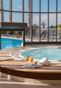 马赛金色郁金香马西利亚别墅酒店的游泳池前的桌子上摆放着两杯饮料的游泳池
