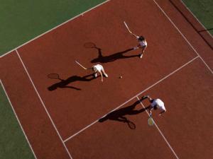 莱奥冈Hotel Krallerhof的三人在网球场打网球