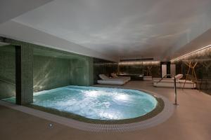 阿威罗Hotel Afonso V & SPA的带沙发和椅子的客房内的按摩浴缸
