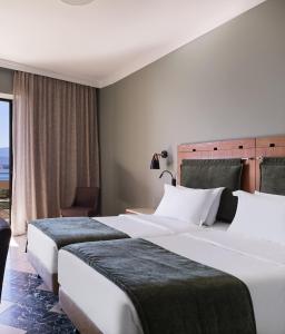 伊斯米亚Kalamaki Beach Resort的配有窗户的酒店客房内的两张床