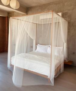 丰盛港BASED - Mersing的卧室配有带白色床单和枕头的天蓬床。