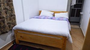 阿鲁沙Meru Farm House的一张带白色床单和枕头的小床