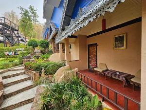 清迈Phu Jaya Floresta Resort by ALPHATEL的一座带门廊的建筑,设有长凳和楼梯