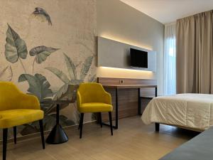 特拉帕尼法德拉中央酒店的一间卧室配有一张床和一张带两张黄色椅子的桌子