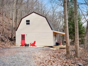 InwoodModern Mountain Cottage w Hot Tub, Fire Pit, WiFi的白色谷仓,设有红色的门和红色椅子