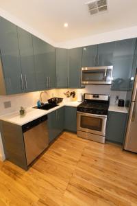 联城Mins to NYC Captivating warm studio apt的厨房配有灰色橱柜和不锈钢用具