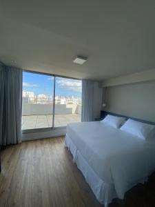 蒙得维的亚Hotel Ciudadano Suites的卧室设有白色的床和大窗户