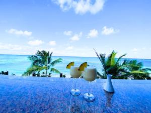 蓬塔卡纳CARAIBICO STUDIOS Beach Club & Pool的桌子上两杯,底下是海洋