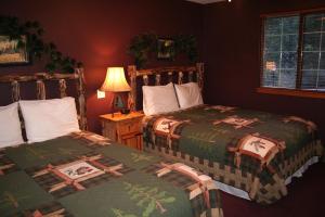 埃斯蒂斯帕克Timber Creek Chalets- 6 chalet的一间卧室设有两张床和一张桌子上的台灯。