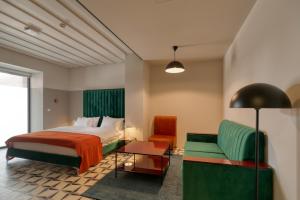 久姆里Manifest Restaurant and Hotel Gyumri的一间卧室配有一张床、一张沙发和一把椅子
