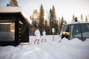 罗瓦涅米Nova Galaxy Village的两个人站在雪上,站在一辆面包车旁边