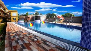 曼达莫尼Saikat Saranya Resort, Mandarmoni Beach的一座大楼内的游泳池,配有椅子和遮阳伞
