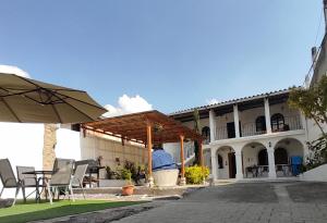 危地马拉安地瓜Blue Moon Hostel的大楼前的带椅子和遮阳伞的天井