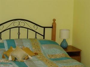 BallymoteThe Gardener's Cottage的一张带枕头的床和一张桌子上的台灯