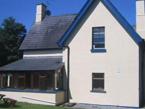 BallymoteThe Gardener's Cottage的白色的房子,有蓝色的屋顶和长凳