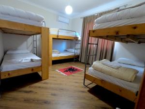 地拉那Left and Right Hostel的带三张双层床的客房和红色地毯