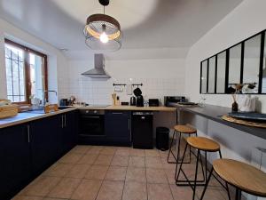 莫雷卢安河L'Echappée Morétaine - Cœur de Moret的厨房配有黑色橱柜、桌子和凳子