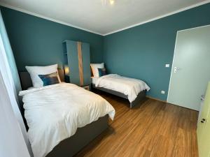 马尔JUNX Bude的一间卧室设有两张带蓝色墙壁和木地板的床。