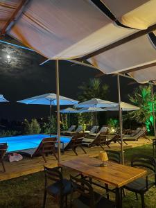达特恰MAVİ ROTA BUTİK OTEL的一个带桌子和遮阳伞的庭院和一个游泳池