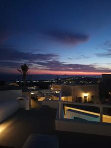 皮尔戈斯Astivi Santorini Apartments的棕榈树建筑的夜景