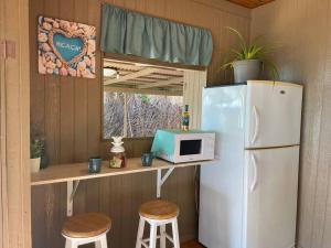 阿瓦托鲁Rangiroa Sunny House的厨房配有冰箱、微波炉和2张凳子