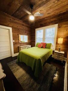 拉斐特Spacious Waterfront Cottage + 2.5 Acres on the Bay的木制客房内的一间卧室配有一张绿色的床