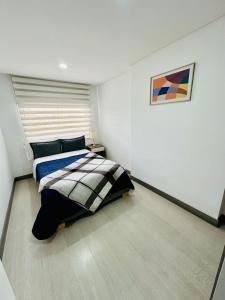 波哥大Magnifico y confortable apartamento amoblado # 303的卧室配有一张床,墙上挂有绘画作品