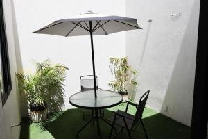 瓜达拉哈拉Aura Hotel boutique的天井上配有一张桌子和两把椅子以及一把遮阳伞。