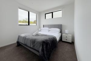 奥克兰Modern 3-bds townhouse in South Auckland的一间白色卧室,配有床和2个窗户