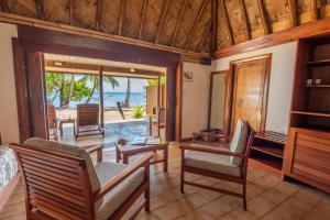Toberua托伯岛度假酒店的客厅配有桌椅,享有海景