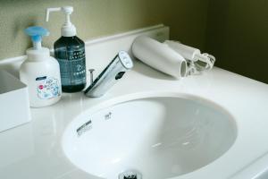 弟子屈町TESHIKAGA HOSTEL MISATO的浴室水槽、一瓶清洁剂和一部电话
