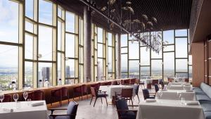 墨尔本The Ritz-Carlton, Melbourne的餐厅设有桌椅和大窗户。