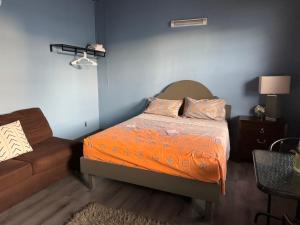Branns HamletJJ Guest House的一间卧室配有一张带橙色棉被的床和一张沙发