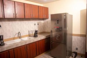 瓦加杜古Kadoued Furnished Apartment 2 Bedroom的厨房配有不锈钢冰箱和木制橱柜