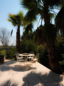 瑞维尼亚克La palmeraie - Piscine vue golf的棕榈树庭院内的桌椅