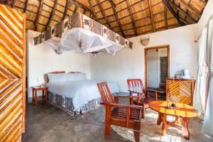 KakumbiNjobvu Safari的卧室配有一张床和一张桌子及椅子