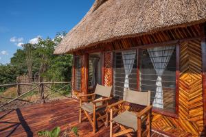 KakumbiNjobvu Safari的小屋设有两把椅子和茅草屋顶