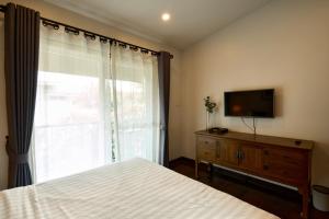 清迈Teera villa chiang mai ทีร่าวิลล่าเชียงใหม่的一间卧室设有一张床、一台电视和一个窗口。